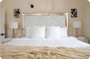 a bedroom with a large white bed and two lamps at Barefoot Bliss Short Term Rental with pool in Colbeck Manor in Claremont +16 photos
