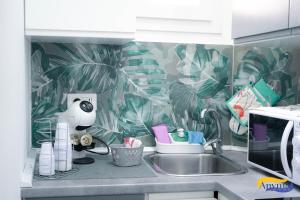 a kitchen counter with a sink and a tropical wallpaper at Anyma Home in Crotone