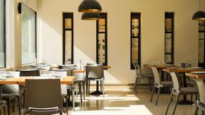 restauracja ze stołami, krzesłami i oknami w obiekcie Vértice Sevilla w Sewilli