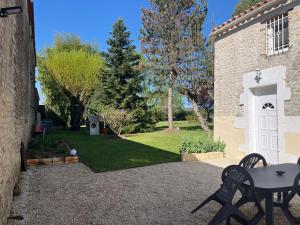 a patio with a table and chairs in a yard at Les granges in Bernay
