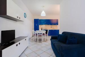 een woonkamer met een blauwe bank en een keuken bij Villa Mery Villaggio Chiusurelle in Torre Lapillo