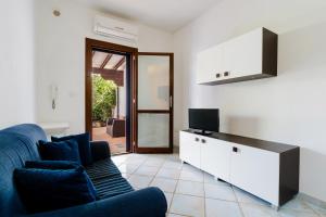 een woonkamer met een blauwe bank en een tv bij Villa Mery Villaggio Chiusurelle in Torre Lapillo