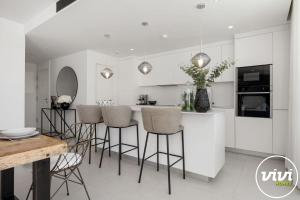 a kitchen with white cabinets and bar stools at ViVi Homes - Casa Española in Fuengirola