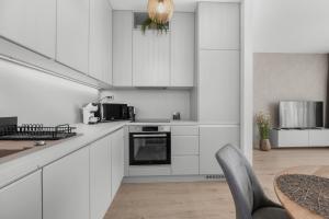 a white kitchen with white cabinets and a table at Sunny, Brand New, Luxury Apartment in Bratislava