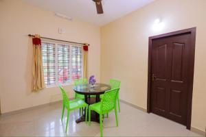 a dining room with a table and green chairs at sky blue villa in Vythiri