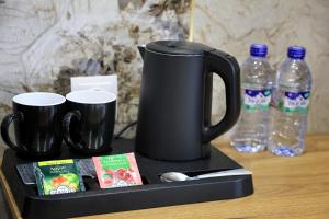 a tray with a coffee pot and two bottles of water at Intercity Hotel Tashkent by Maskan in Tashkent