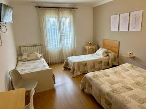 a bedroom with two beds and a table and a chair at Hostal Estació in Puigcerdà