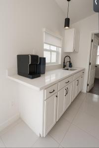 a white kitchen with a sink and a microwave at Modern Home - Termpurpedic Queen bed, Laundry, Free Parkging, EV Tesla in Hollywood