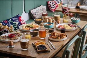 a wooden table topped with plates of food and drinks at Hotel Cervantes by Happyculture in Paris