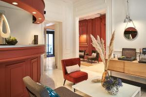 a living room with a red chair and a table at Hotel Cervantes by Happyculture in Paris