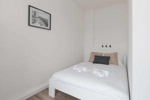 a white bed in a room with white walls at TERRASSE DU MAINE - Centre ville - Wifi in Saint-Nazaire