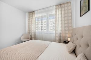 ein weißes Schlafzimmer mit einem Bett und einem Fenster in der Unterkunft Brand New, Cozy Free parking apartment in Bratislava