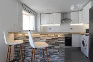 a kitchen with two white chairs at a counter at Apartamento Ama Altea in Altea