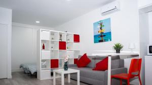 a living room with a gray couch and red pillows at Studio 1 Soto Parking Renfe in Torrejón de Ardoz +3 photos