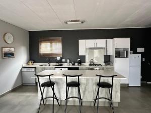 a kitchen with a counter and three bar stools at MAYAMUYE Lifestyles in Nelspruit