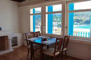 a dining room with a table and chairs and windows at Chic Magnificent Sea View Suite in Andros