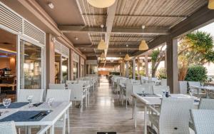 a restaurant with white tables and white chairs at Black & White Resort in Xylokastro