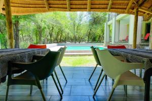 a table and chairs with a view of a pool at Mshengu Kruger Lodge in Marloth Park
