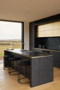 a kitchen with a large black island with bar stools at Zoarii Luxury Beach Front Wellness Stay in Ventnor