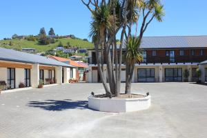 a courtyard with palm trees in front of a building at Heritage Court Motor Lodge Oamaru in Oamaru