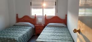 two twin beds in a room with a window at Apartamento en Playa Honda - La Manga in Cartagena