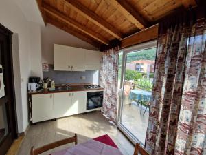 a kitchen with white cabinets and a large window at Guest House Gordana in Banjol