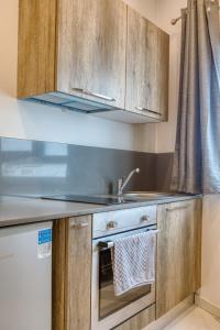 a kitchen with wooden cabinets and a sink at Stylish Apartment in Bay Square 2 in St Paul's Bay