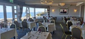 a restaurant with white tables and chairs and windows at Royal Court Hotel in Portrush