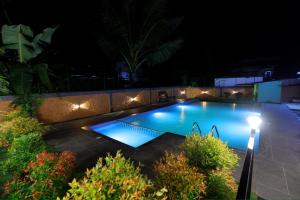 a swimming pool lit up at night with lights at sky blue villa in Vythiri
