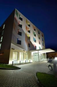 un bâtiment avec des fenêtres colorées dans un parking la nuit dans l'établissement Hotel Euro, à Pardubice