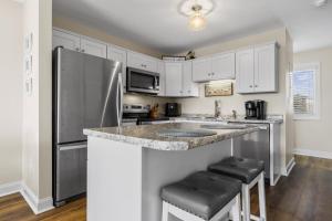 une cuisine avec des armoires blanches et un réfrigérateur en acier inoxydable dans l'établissement The Salty Pelican townhouse, à Atlantic Beach