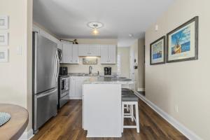 une cuisine avec des armoires blanches et un réfrigérateur en acier inoxydable dans l'établissement The Salty Pelican townhouse, à Atlantic Beach