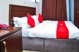 a bedroom with a bed with red pillows and a telephone at Nafelis Hotel Enugu in Enugu
