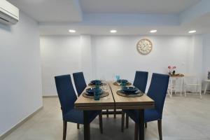 a dining room table with blue chairs and a clock at Apartamento Avenida Altea 19 in Altea