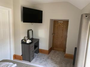 a bedroom with a bed and a television and a door at George and Dragon in Holmesfield +53 photos