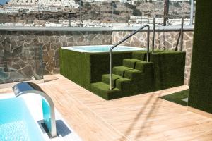 a swimming pool with green stairs on a building at IG Nachosol Atlantic & Yaizasol by Servatur - Adults Only in Puerto Rico de Gran Canaria