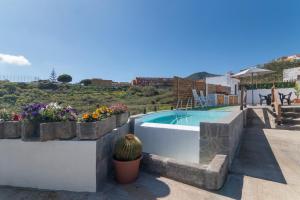 a villa with a swimming pool and some flowers at Los Barranquillos in Firgas