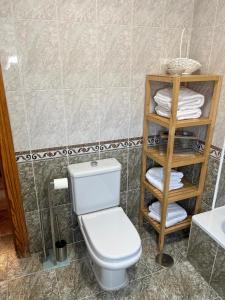 a bathroom with a toilet and a shelf with towels at Apartamento 7 adultos in Rueda
