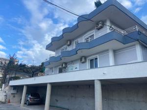 a blue and white building with a car parked in front at Vila Floban & MIRDAR KOSHI in Sarandë