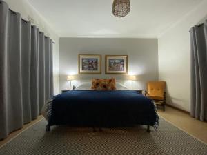 a bedroom with a blue bed with two lamps and a chair at Harmonie Hills in Sukani