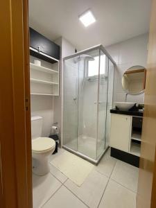 a bathroom with a toilet and a glass shower at Apartamento Pé na Areia Barra Velha in Barra Velha