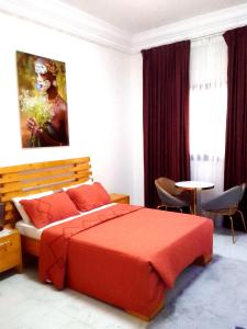 a bedroom with a red bed and a table and chairs at La Rouah Mishkan in Dakar