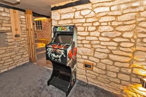 un sistema de videojuegos en una habitación con una pared de piedra en Finest Retreats - Ttich Manor Retreat, en Milton Keynes