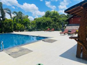 una piscina con 2 bancos junto a un edificio en Elephant Entrance, en Habarana