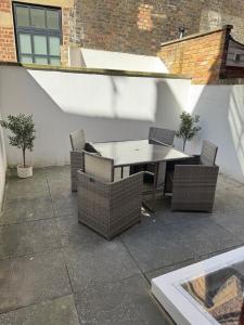 a patio with a table and wicker chairs at Cosy Townhouse In Central London in London