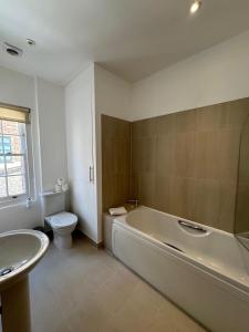 a bathroom with a tub and a toilet and a sink at Cosy Townhouse In Central London in London