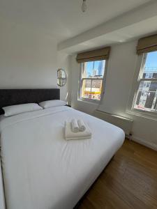 a bedroom with a large white bed with two towels on it at Cosy Townhouse In Central London in London +7 photos