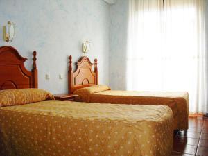 um quarto de hotel com duas camas e uma janela em Hostal Bellas em Ávila
