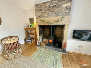sala de estar con chimenea de piedra y TV en The Nookery - Cosy Cottage in the Heart of Town, en Alston