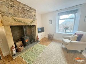 sala de estar con chimenea, sofá y silla en The Nookery - Cosy Cottage in the Heart of Town, en Alston